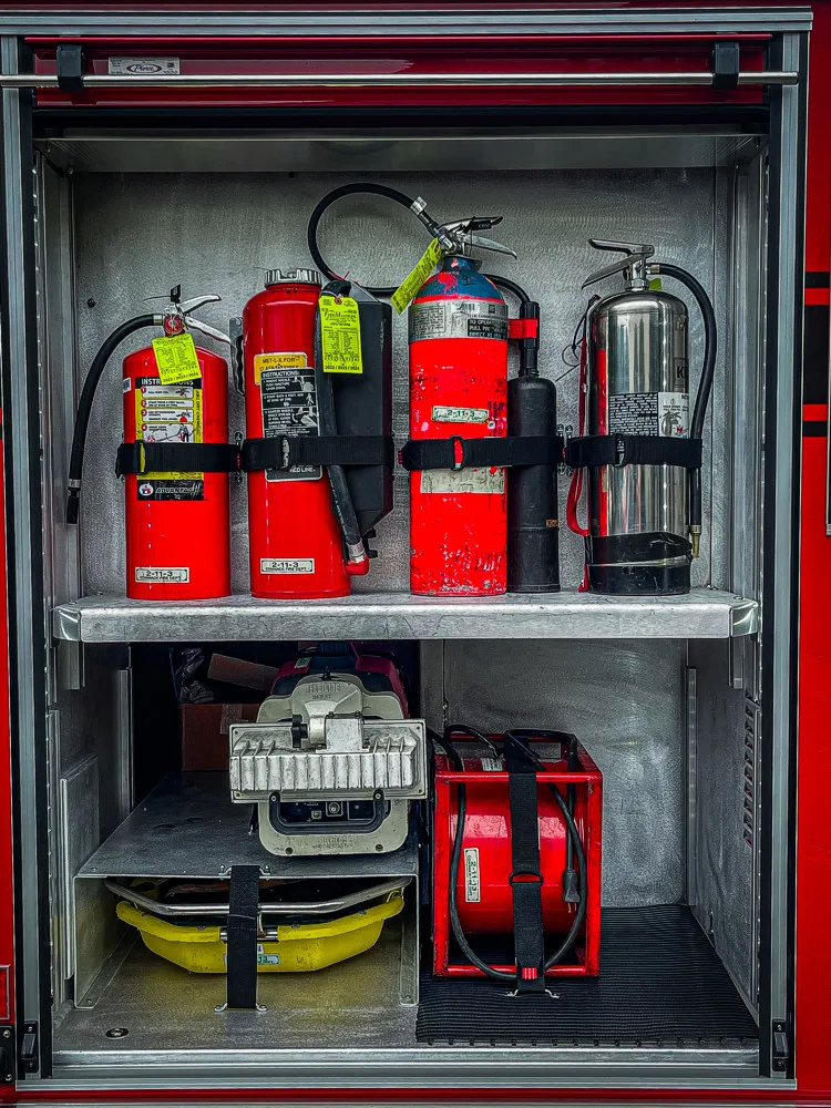 Open side compartment showing extinguishers and equipment storage bins