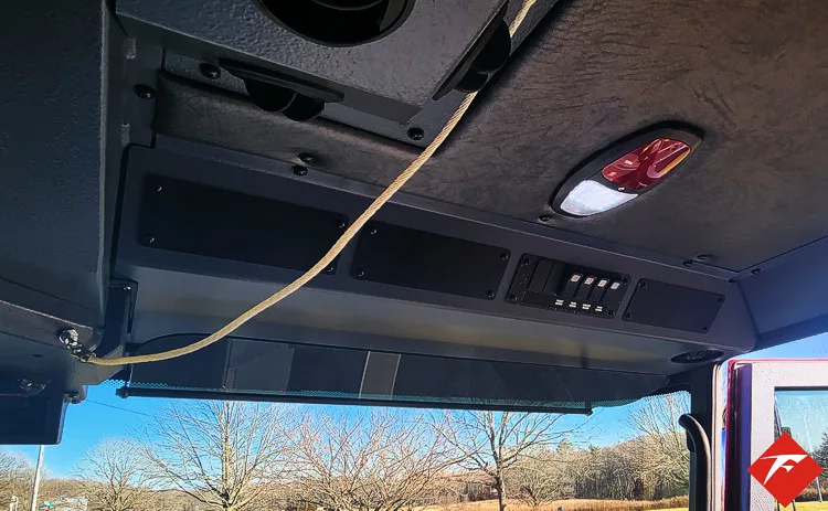 Cab overhead console close-up showing control strip and wiring conduit