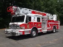 Tower ladder front-left exterior view showing enclosed cab and ladder bed