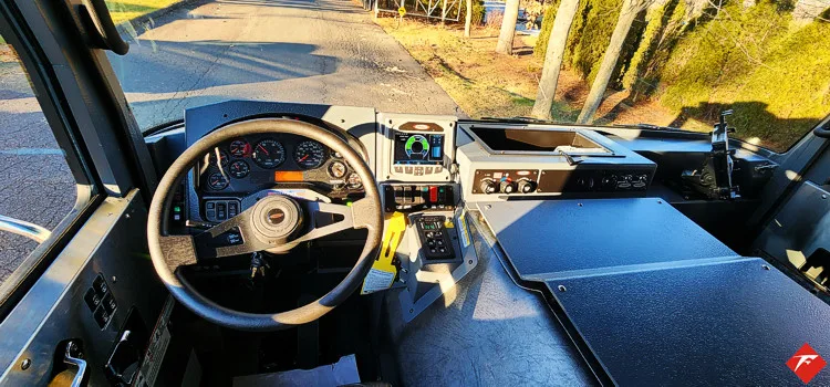 Driver cockpit view showing steering wheel, dash controls, and center display