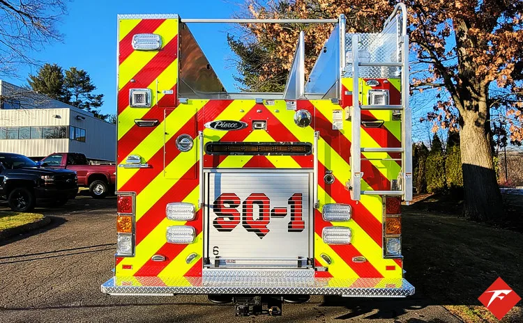 Rear view showing red-and-yellow chevrons, rear lights, and tailboard