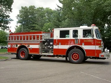 Driver-side full profile showing side pump controls, hosebed rail, and compartment layout.