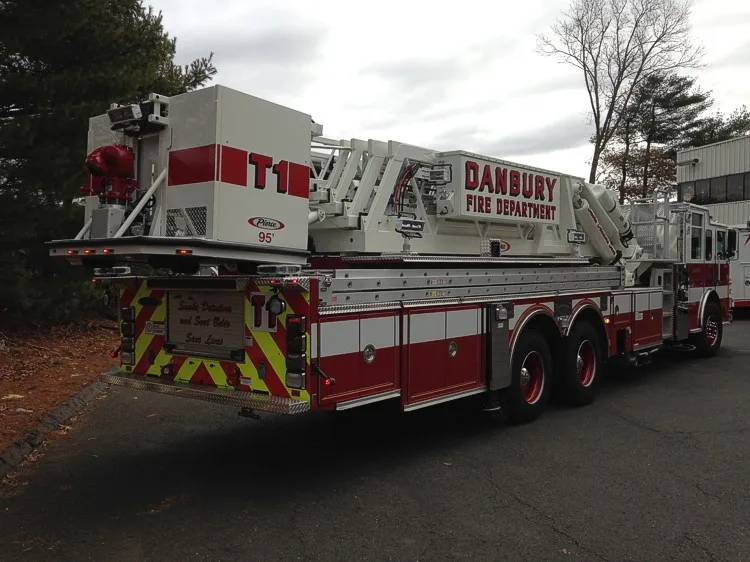 Rear-left exterior view showing bucket, rear chevrons, and ladder bed
