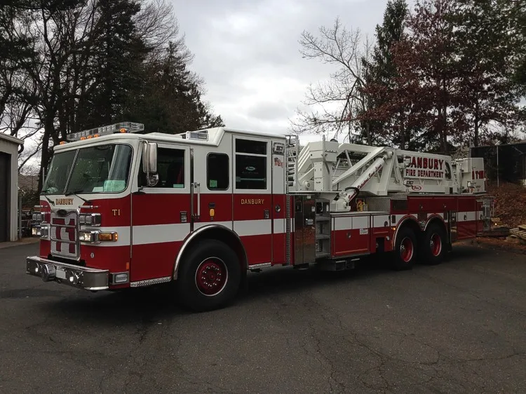 Driver-side full profile showing aerial ladder body and tandem rear wheels