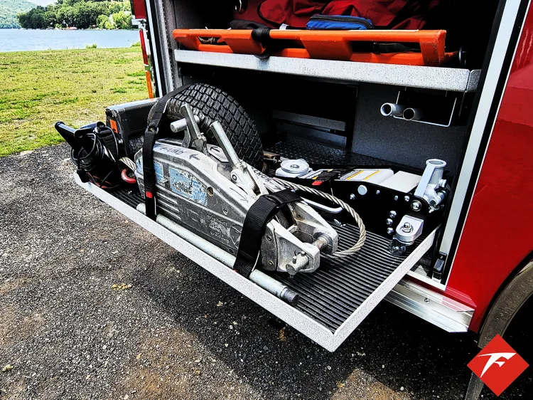 Open lower compartment showing strapped extrication tools on pull-out tray