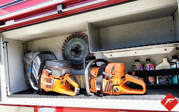 Open side compartment showing chainsaws, saw cases, and hand tools