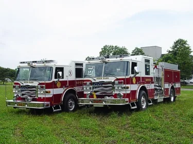 Front-quarter view of two pumpers showing cabs, bumpers, and side panels