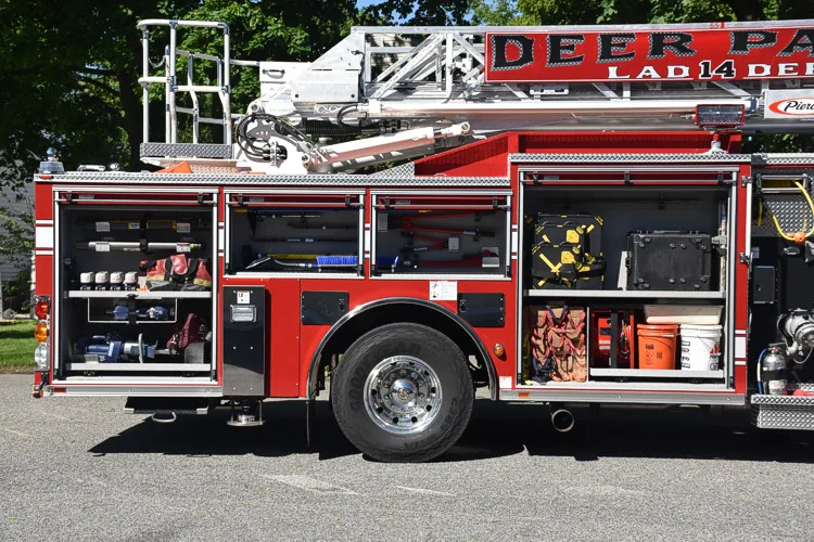 Driver-side mid-body view showing open compartments and tandem rear wheel area