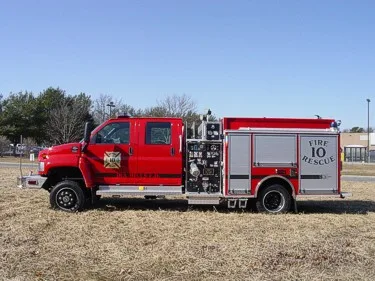 Driver-side full profile showing the side pump panel controls, rear compartments, and wheel area.