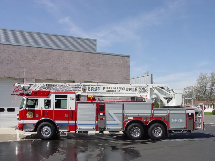 Driver-side full profile showing the stowed aerial ladder, side compartments, and tandem wheel area.