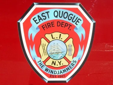 Close-up of a shield-style side door emblem on red paint with decorative fire service symbols.