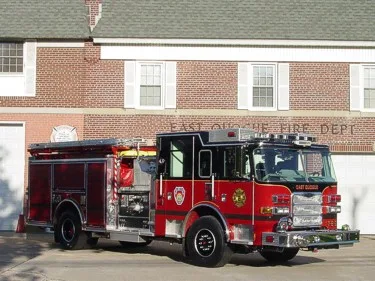 Front left side view showing crosslay area, top hose storage, and compartment doors along the body.