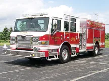 Wide front-left view of the rescue pumper parked in the lot with full side body visible.