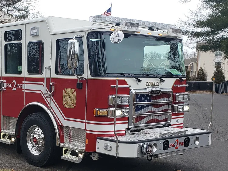 Pumper front-left exterior view parked roadside with side compartments closed