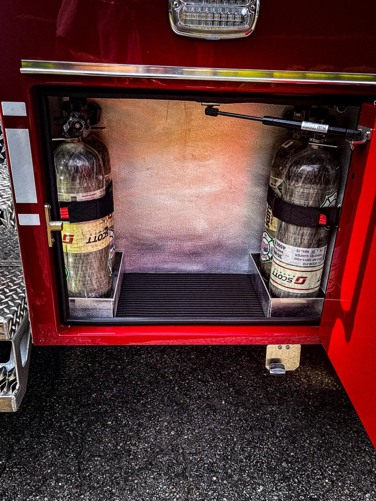 Open lower compartment showing mounted extinguishers and short tools