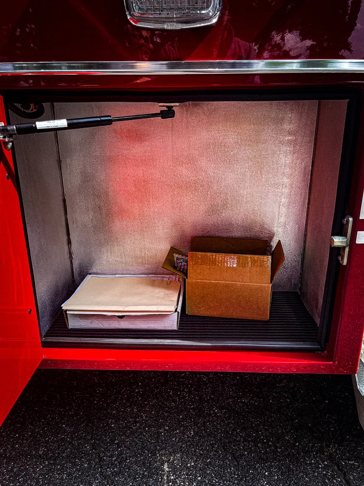 Open side compartment showing small cardboard box on lower shelf