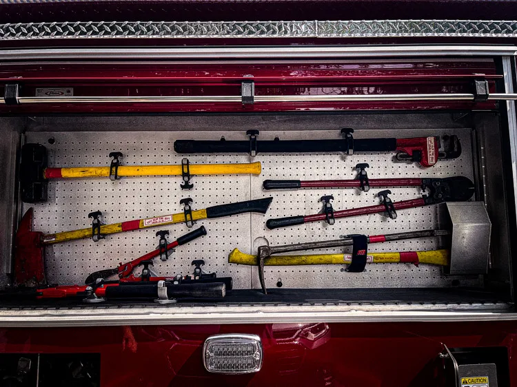 Open side compartment showing mounted long tools and pike poles