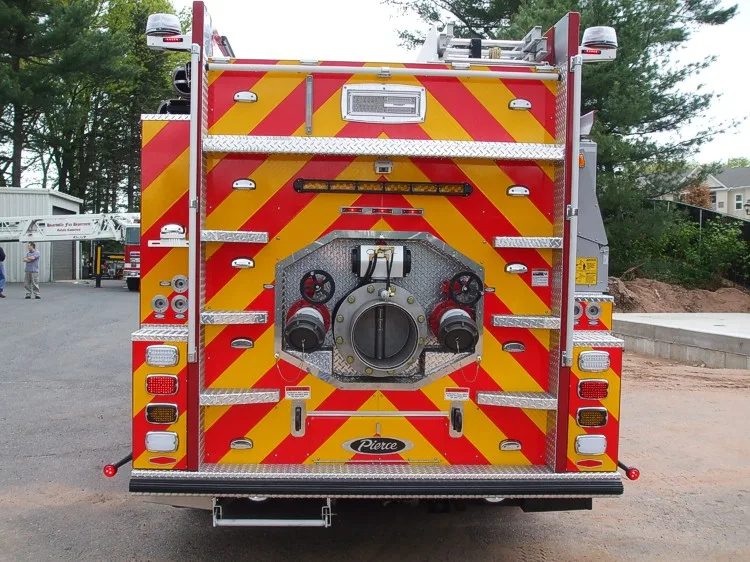 Straight rear view with red-yellow chevrons, rear intake and discharge fittings, and tail light stack.