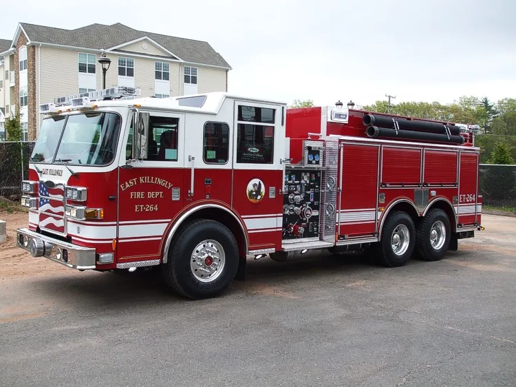 Front left side view showing cab doors, pump panel, roll-up compartments, and rear tandem axles.