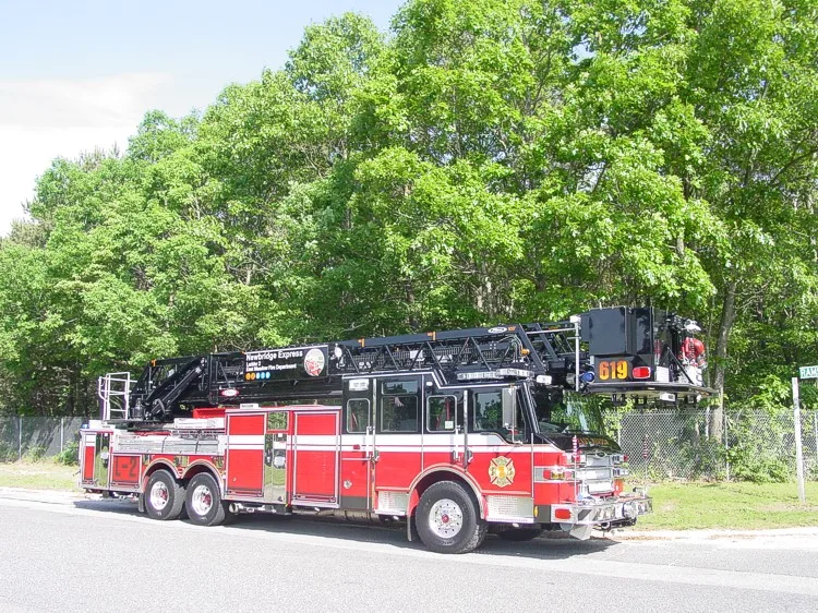 Front-right wide view showing the tower ladder cab face, side body, and aerial ladder sections.