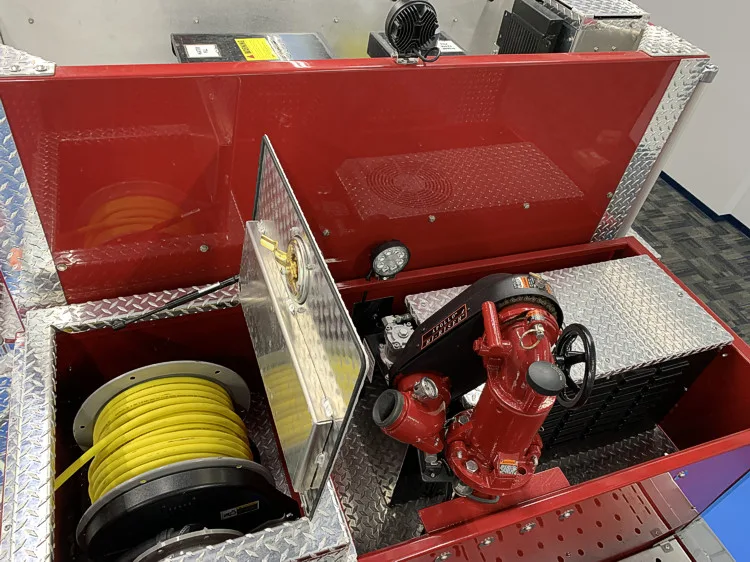 Top deck compartment close-up showing hose roll and monitor piping