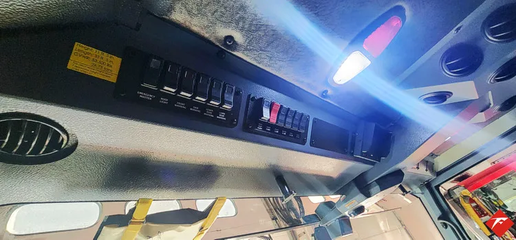 Cab ceiling control close-up showing overhead switches and warning labels