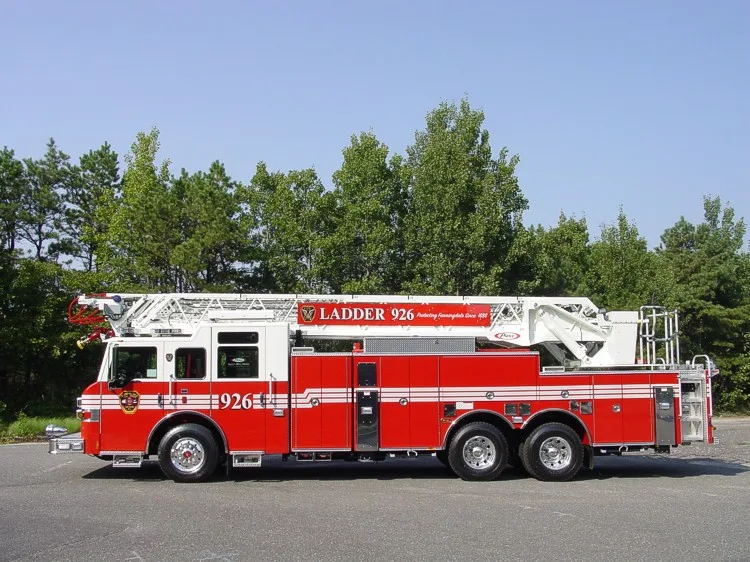 Driver-side profile view showing the stowed aerial ladder, side compartments, and tandem rear wheel area.