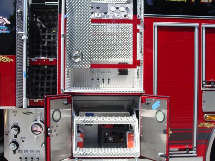 Close-up of an opened side equipment compartment with pull-out tray, shelves, and control switches.