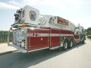 Rear-right exterior view showing ladder bed, tandem rear axles, and side body