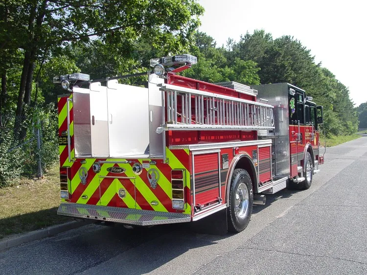 Rear-left exterior view showing rear chevrons, side ladder storage, and rear body compartments.