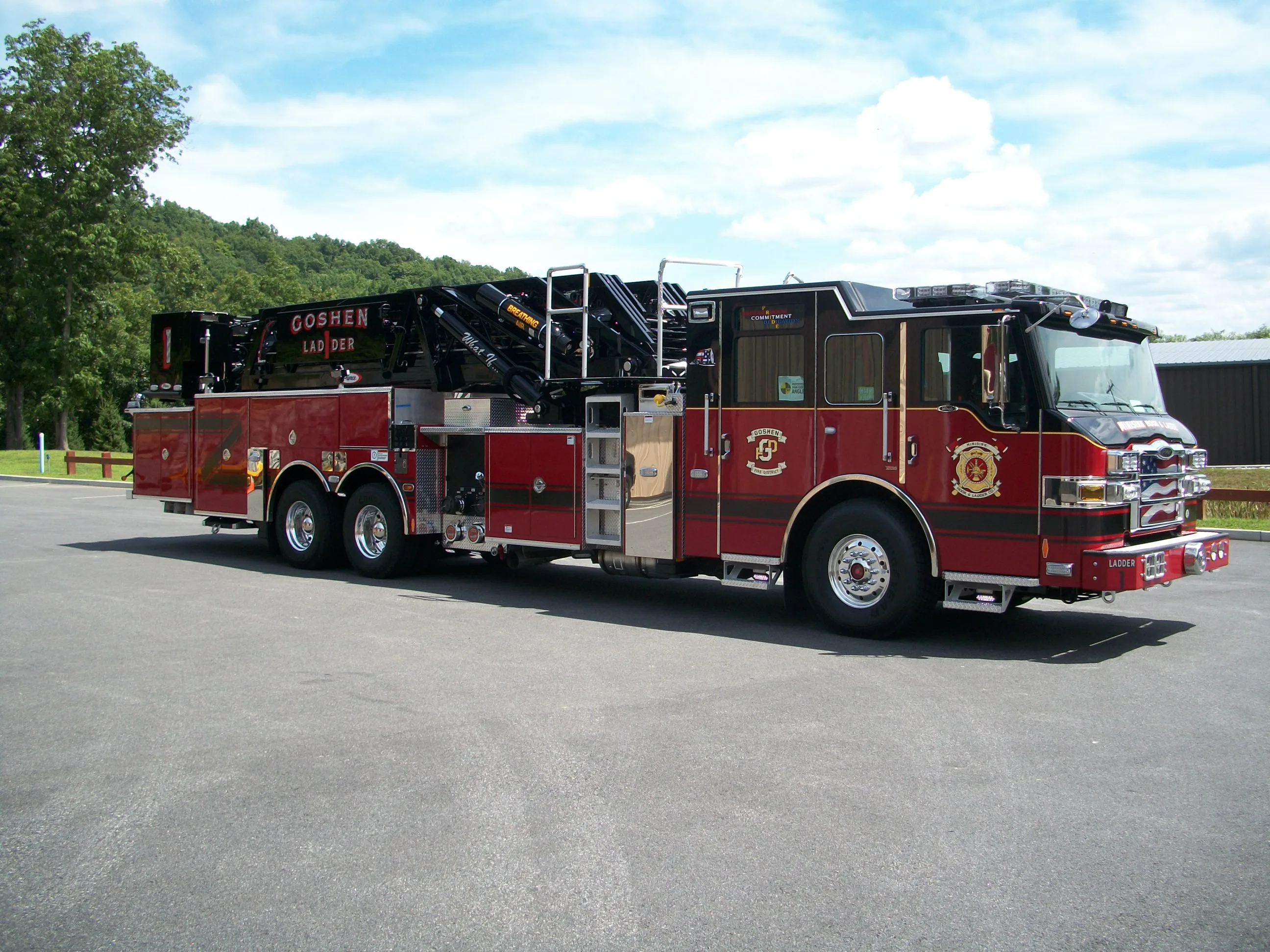 Passenger-side full profile showing the stowed aerial ladder, side compartments, and tandem wheel area.