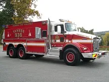 Wide driver-side three-quarter view of the tanker showing the commercial cab and tandem rear wheel area.