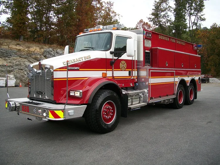 Front-left exterior view showing the grille, bumper, cab, and side tank body compartments.