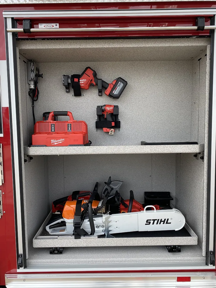 Open side compartment showing shelf with power saw and equipment case