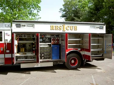 Passenger-side view with compartments open showing slide-out trays and equipment racks