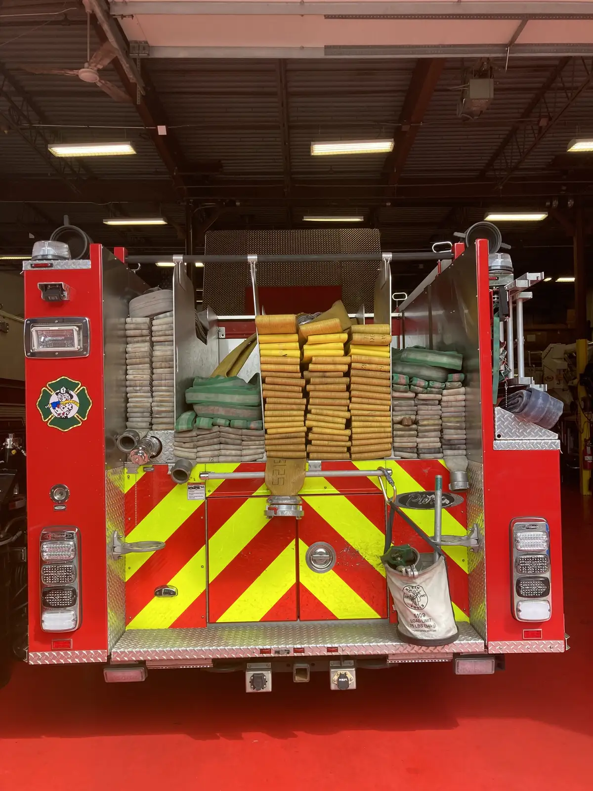Rear hosebed loaded with stacked hose bundles above chevron doors