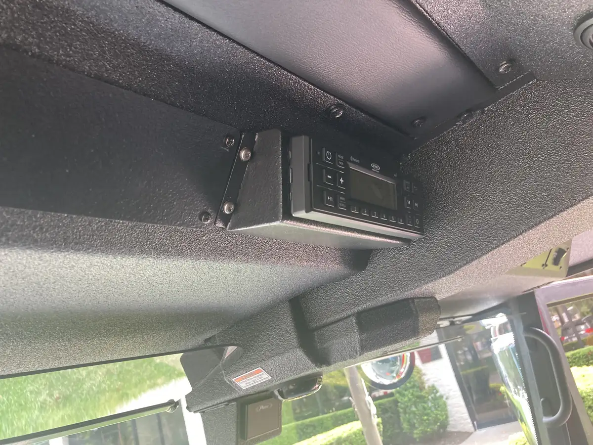 Cab ceiling vent cluster close-up with speaker and warning label