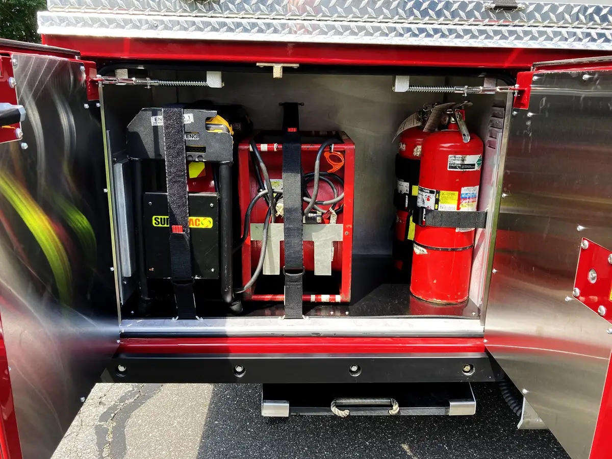 Rear-side compartment open showing long-handled tool storage and lower tray