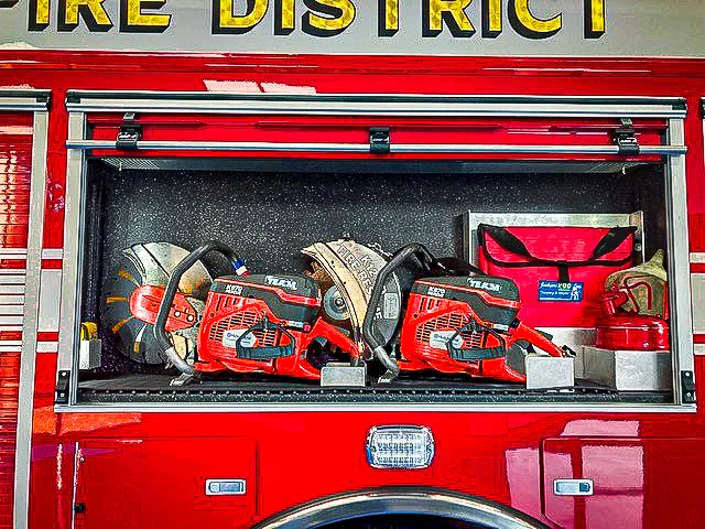 Open side compartment showing rescue tools, chainsaw case, and bags
