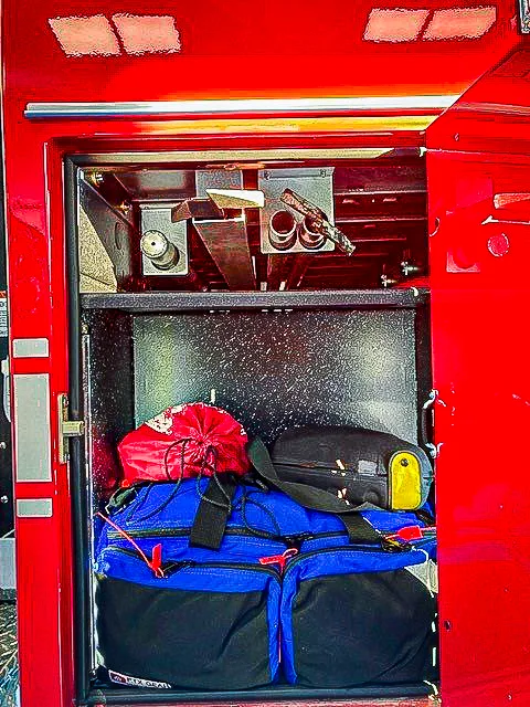 Open side compartment showing folded blue tarp and soft bag on shelf