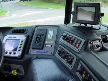 Driver cockpit console close-up showing monitor, switches, and control buttons