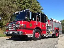 Wide front-left view of the pumper parked roadside with full side body visible.