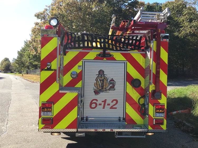 Straight rear view with red-yellow chevrons, rear hosebed netting, and center rear compartment door.