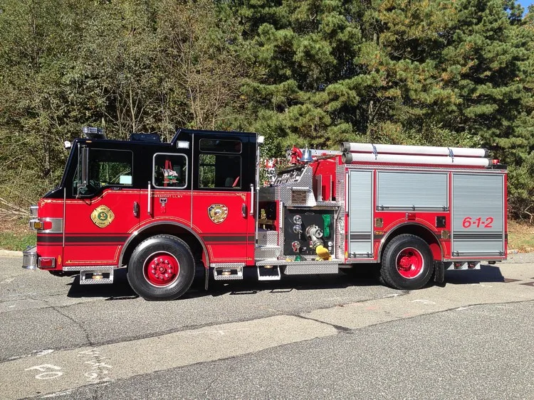 Driver-side full profile showing pump panel controls, side compartments, and rear wheel area.