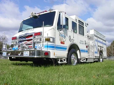 Low front-left angle showing grille, bumper, warning lights, and side body profile.