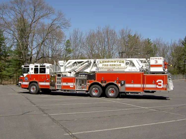 Wide left-side profile showing full ladder length, turntable controls, and tandem axle wheel area.