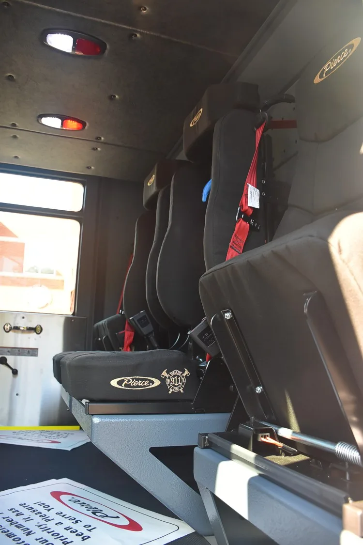 Cab interior bench-seat view showing three rear seats with red harness straps