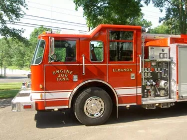 Left-side mid-cab close view highlighting cab doors, front wheel area, and pump panel controls behind the cab.