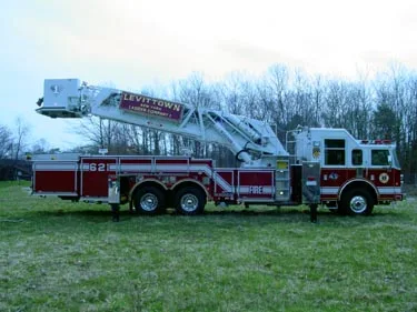 Passenger-side full profile showing tower ladder body, bucket, and tandem rear axles