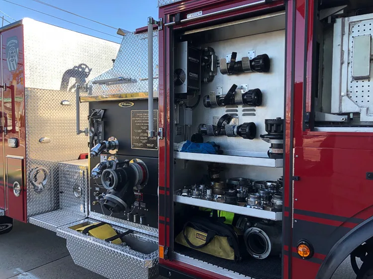 Open side compartment showing stacked equipment shelves and tool storage